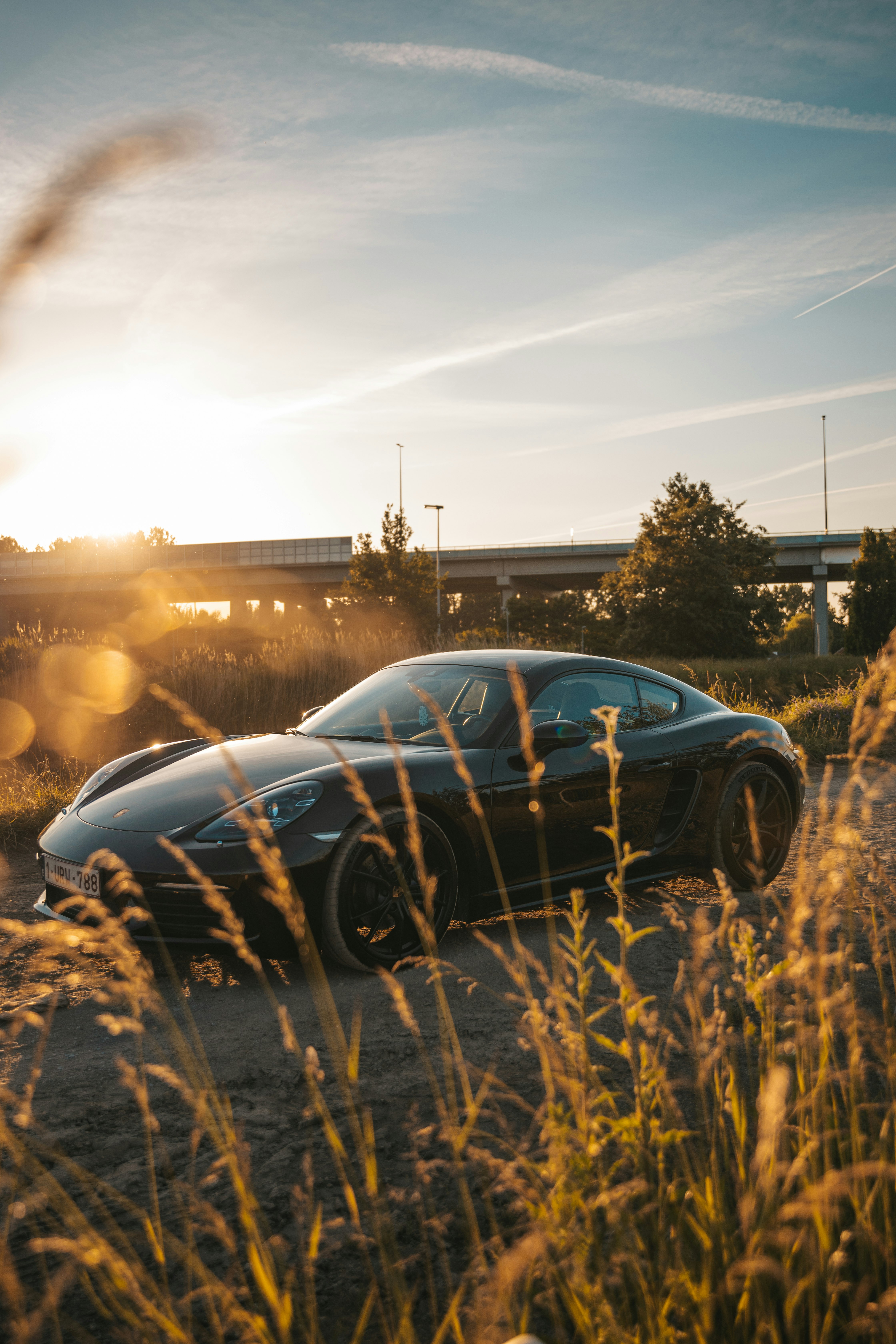 blue car parked on brown grass field during sunset